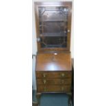 A walnut bureau bookcase with single glazed door over a base with three drawers and drop front,