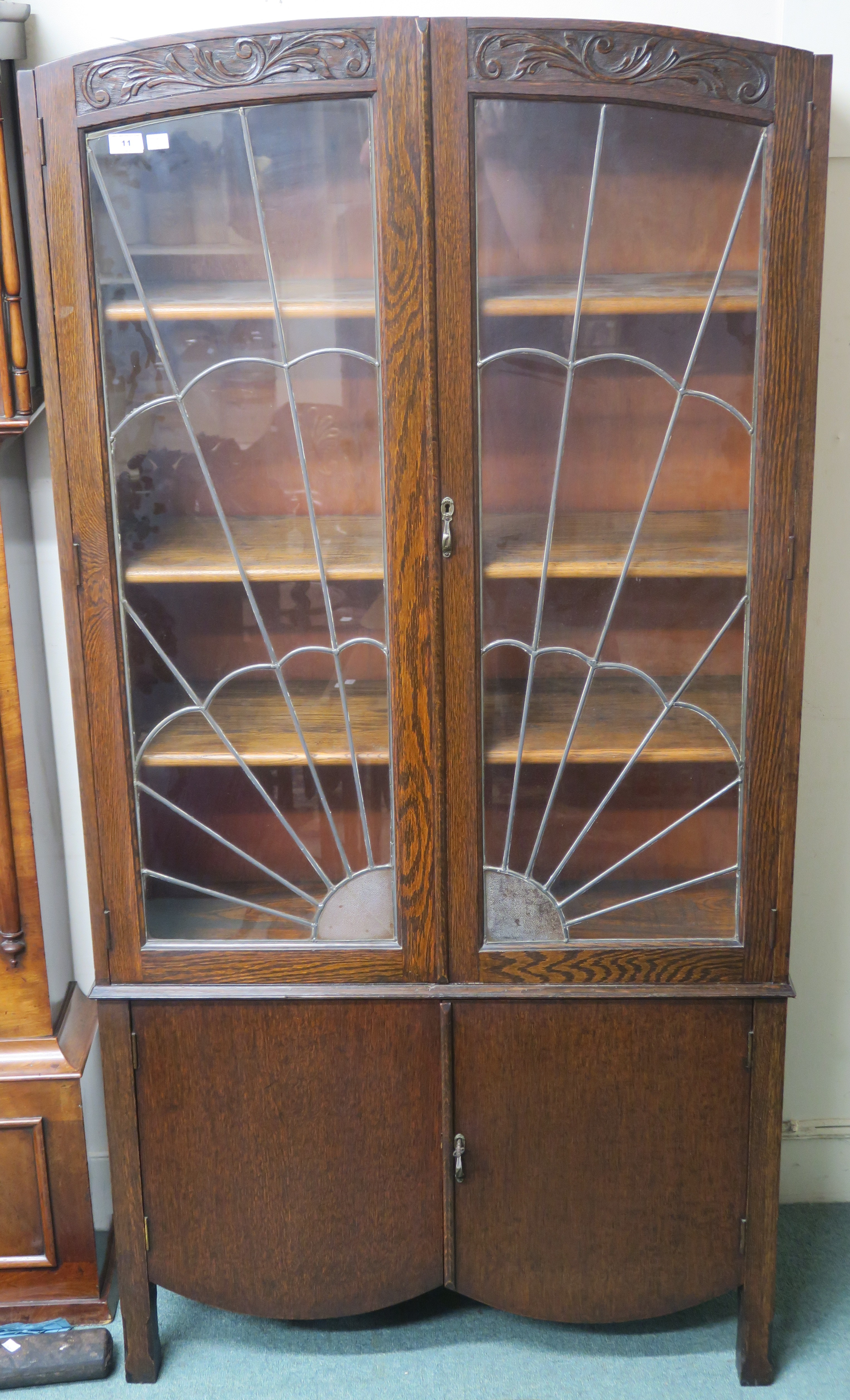 An Art Deco oak bookcase with sunburst leaded glass with carved top over two doors,183cm high x 92cm