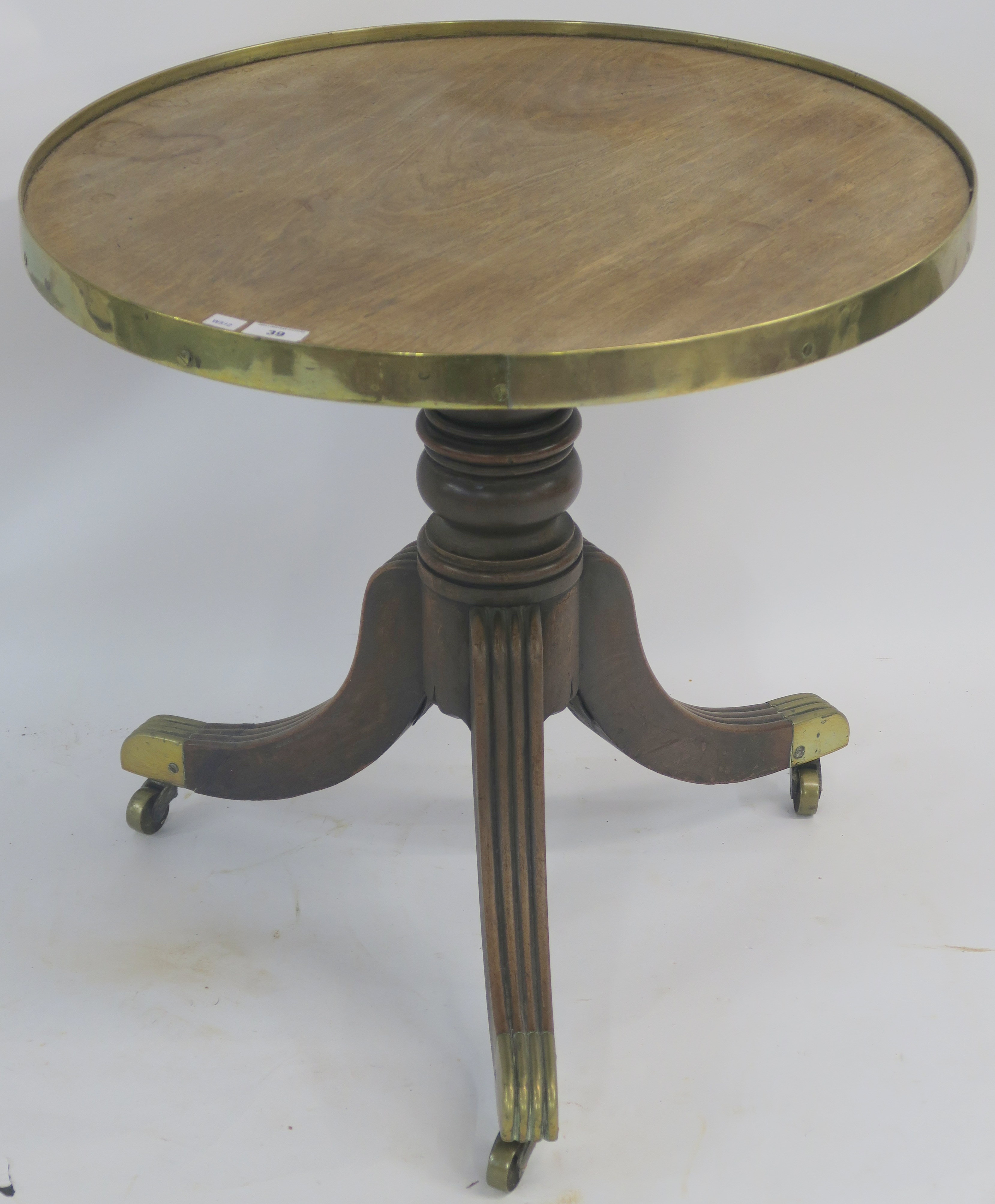 A Victorian mahogany circular table with brass frame on a turned baluster support on tripod base