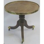 A Victorian mahogany circular table with brass frame on a turned baluster support on tripod base