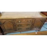 An early 20th century oak sideboard with three central graduated drawers flanked by two doors,