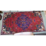 A red ground eastern rug with central medallion. 210cm long and 114cm wide Condition Report: