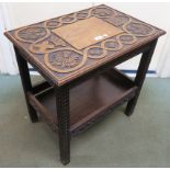 An early 20th century oak two tier occasional table with extensive carving to top depicting