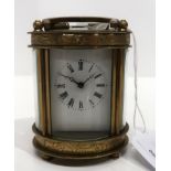 A small oval brass and glass carriage clock with roman numerals Condition Report: Available upon