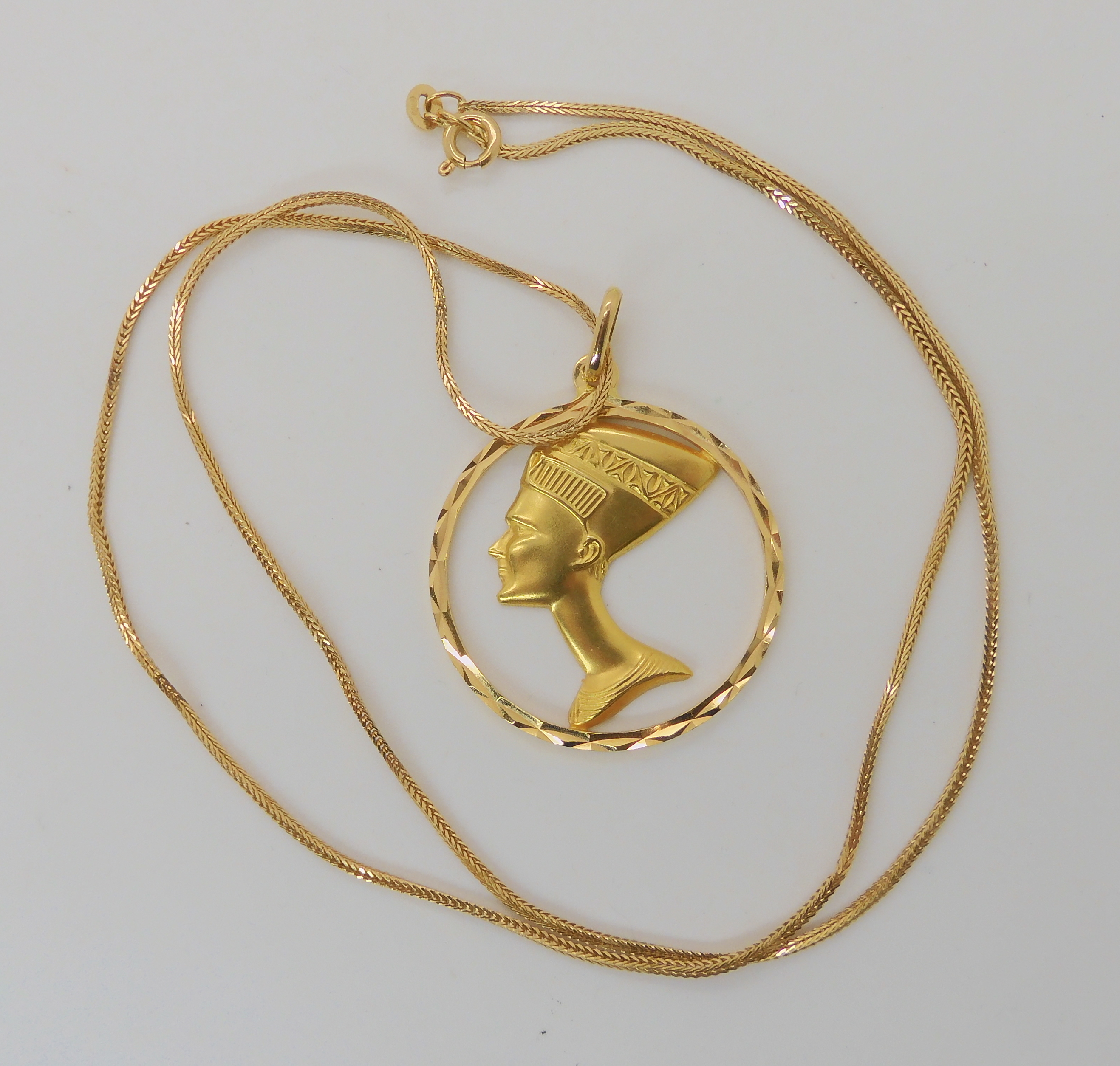A 18k Nefertiti pendant diameter 3.5cm, on an 18ct gold Italian herringbone chain length 60cm
