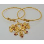 Two bright yellow metal bangles and a red gem set pendant, weight together 40.5gms Condition Report: