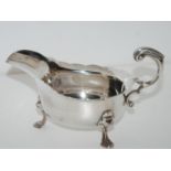 A silver sauce boat, London 1903 with open scrolling handle on three pad feet, 19cm long, 295gms