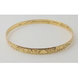 A 9ct gold engraved bangle, diameter 6.8cm, width 0.6cm, inscribed to the interior, weight 12.4gms