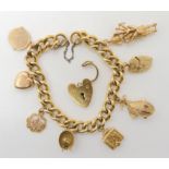 A gold plated curb chain bracelet with eight attached 9ct charms, to include a cat in a wicker egg