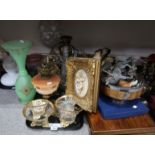 A selection of brass oil lamps with various shades, a green and gilt glass vase, resin figures of