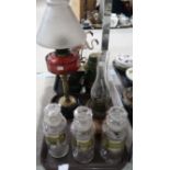 Three chemists storage jars with glass labels, a brass and cranberry oil lamp with frosted shade and