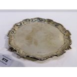 A silver card tray Sheffield 1936, circular with scalloped stepped edge on three scrolling feet 20.5