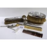 A lot comprising a pair of silver backed hair brushes, a comb, a silver spoon and pusher & a