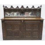 A 17TH CENTURY DESIGN OAK MIRROR BACK SIDEBOARD applied with masks, above a pair of panelled doors