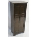 A WYLIE AND LOCHHEAD (GLASGOW) OAK SHOE CUPBOARD the panelled door enclosing three tiers, 126cm