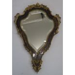 A BOULLE STYLE GILT METAL MOUNTED MIRROR the shield shape with foliate scroll mounts, enclosing a