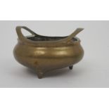 A CHINESE BRASS CENSER with a pair of risen curved handles above a bulbous body and cast with seal
