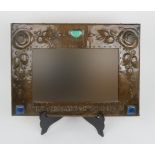 AN ARTS AND CRAFTS COPPER MIRROR of rectangular form with relief decoration of flowers and