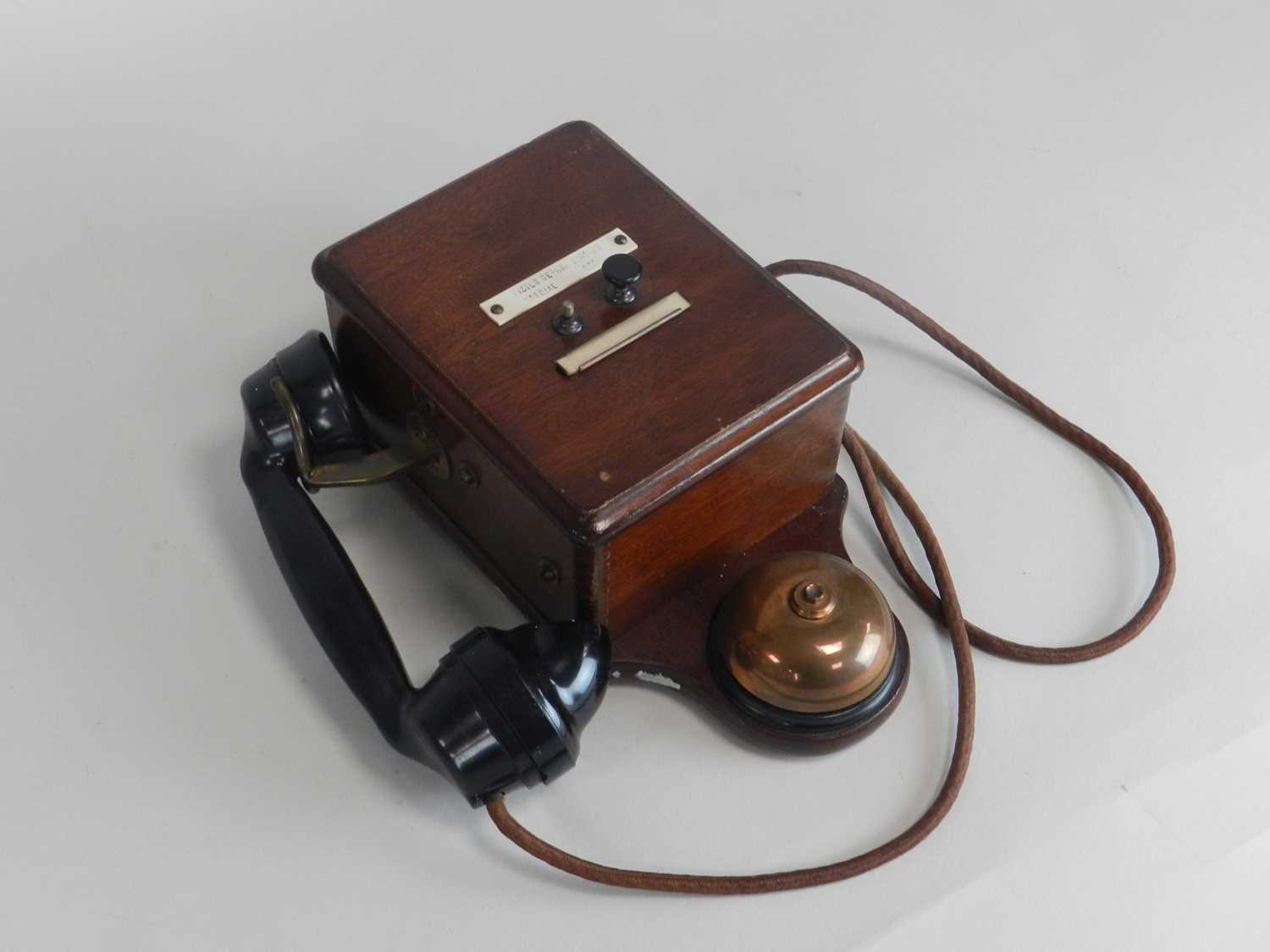 A wall-mounted mahogany-cased telephone, with Bakelite receiver and two push buttons.
