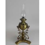 An Edwardian brass oil lamp, with embossed reservoir raised on scroll supports and a trefoil base,