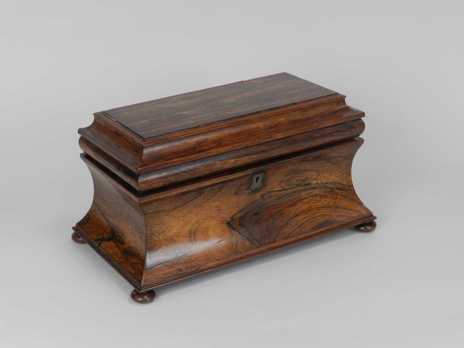 A 19th Century rosewood tea caddy, of sarcophagus form, the interior with two tea boxes flanking a