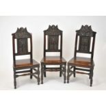 A set of three 17th century oak chairs, each with a foliate carved cresting rail, above a panelled
