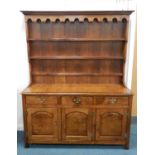 A recent reproduction oak dresser and rack, the cross-banded top above three frieze drawers and