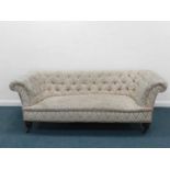 An upholstered Chesterfield sofa, of typical form with button back, raised on mahogany supports with