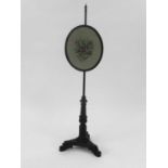 A Victorian rosewood pole screen, the oval screen with needlepoint worked with a flower spray, the