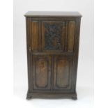 An Edwardian oak collector's or music cabinet, the single carved panelled door opening to an