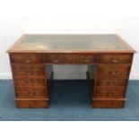 A reproduction walnut pedestal desk, the moulded top with tooled green leather skiver above three
