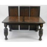 An Edwardian oak dining suite comprising a wind-out dining table, eight cane-seated dining chairs, a