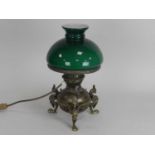 An Edwardian brass oil lamp, the globular reservoir raised on griffin feet, with green glass