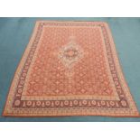 A large Eastern woven wool carpet, the red field populated with a central floral medallion and