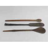 Three Oceanic tribal carved wood ceremonial objects, each of paddle form with turned handles,