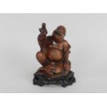 A Chinese carved hardwood figure of a laughing Buddha, modelled seated and accompanied by a boy,