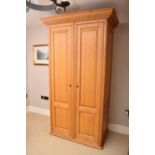 A recent Clive Christian light oak single wardrobe, with dentil cornice above twin panelled doors.