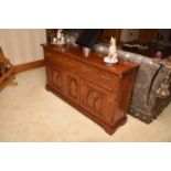 A reproduction Gothic style dresser base, the three frieze drawers with Gothic style brass