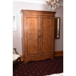 A reproduction walnut double wardrobe, the cavetto cornice above reeded panelled doors, raised on