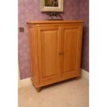 A recent Clive Christian light oak hall cabinet, the moulded top above twin panelled doors and