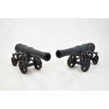 A pair of cast iron ornamental cannon, each 100cm tapering barrel with cast armorial crest, set on a