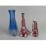 Val St Lambert, circa 1960s, two ruby lamp bases and a blue vase, of wrythen form, two with