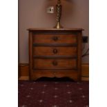 A pair of reproduction walnut bedside chests of three drawers, the moulded top above a slightly