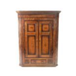 A George III oak cross-banded hanging corner cupboard