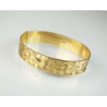 A 9ct gold bright cut engraved hinged bangle