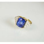 An 18ct gold tanzanite and diamond dress ring, designed as a central cushion cut tanzanite claw