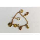 A yellow metal curb link bracelet with charms