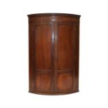 A George III mahogany bow-fronted hanging corner cupboard