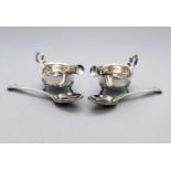A pair of silver sauce boats and a pair of silver spoons