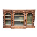 A Victorian carved oak breakfront glazed bookcase